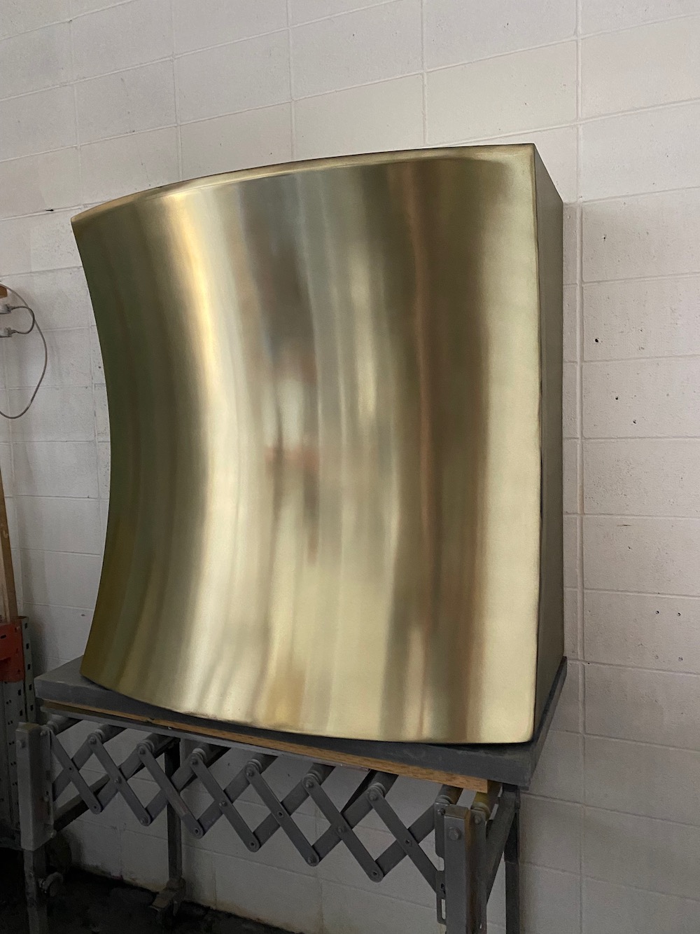 Brass curved range hood in work shop